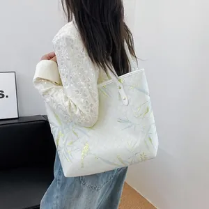 Detailed close-up of white tote bag with light blue and gold bamboo leaf print