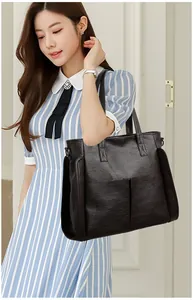 Detail of soft leather tote bag showing lychee grain texture and dual front pockets
