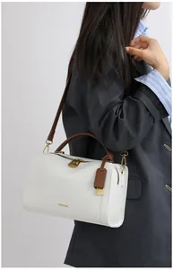 Details der weißen Boston Bag aus Leder mit Litschimuster und braunen Tragegriffen