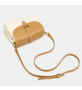 Detail der zweifarbigen Umhängetasche aus Leder in Creme und Camel mit Metallschnalle