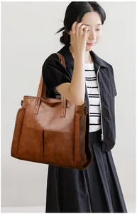 Detailed macro view of vintage brown soft leather tote bag showing large front pockets