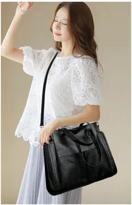 Detail of a large black leather tote bag with side pockets and adjustable shoulder strap