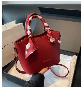 Détail du sac seau rouge avec foulard à cœurs et finitions dorées en coffret cadeau