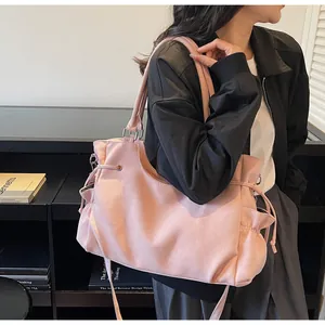 Detalle del bolso tote de ante rosa con bolsillos laterales de cordón y correa ajustable