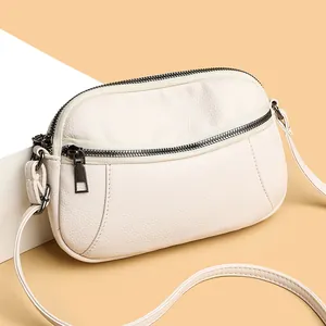 Off-white lychee grain leather crossbody bag with metallic zippers for casual styling