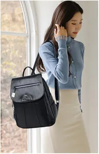 Detail of black pebbled leather backpack showing kangaroo metal logo and side pocket