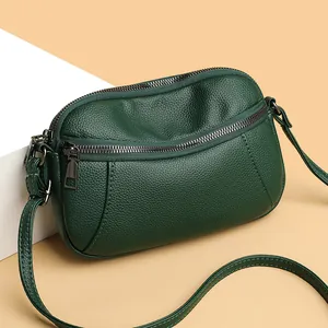 Dark green leather crossbody phone bag with pebble texture and curved zipper design