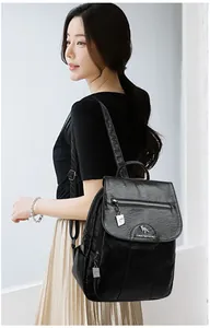 Close-up of black leather backpack featuring metallic kangaroo logo and fine texture detail