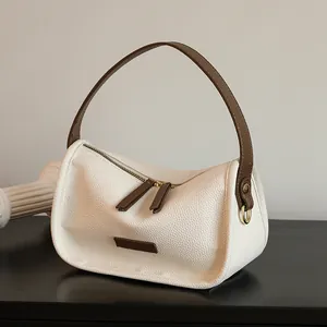 Chic off-white leather shoulder bag with brown handles and elegant gold hardware