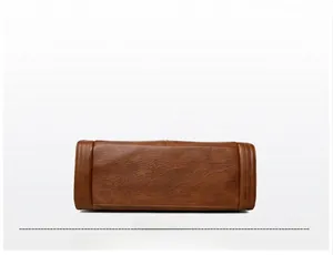 Close-up of the brown leather tote base featuring embossed logo and litchi grain texture