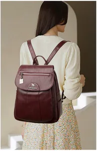 Close-up of deep red leather backpack featuring metallic kangaroo logo and zip pocket detail