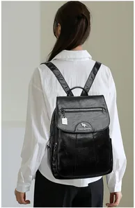 Macro shot of black shiny faux leather backpack showing silver kangaroo logo and side pocket