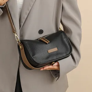 Chic black lychee grain leather shoulder bag with brown accents on a grey blazer model