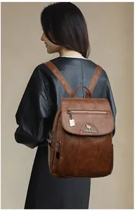 Macro detail of brown leather backpack featuring a silver kangaroo logo and zip chain