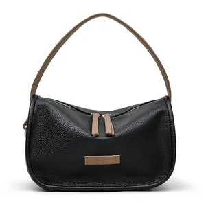 Chic black pebbled leather baguette bag with brown handles and a minimalist design