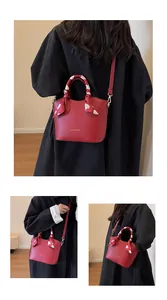 Détail du sac seau rouge avec foulard à motifs cœurs et lettrage doré élégant