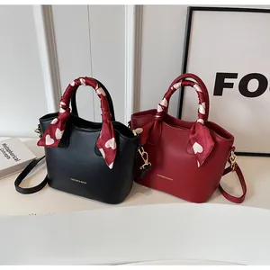 Détail de sacs à main élégants noirs et bordeaux avec foulards en soie et lettrage doré