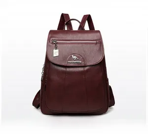 Macro detail of wine red faux leather backpack featuring textured lychee grain and metallic logo