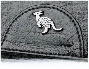 Close-up of silver kangaroo logo and refined litchi texture on black leather backpack