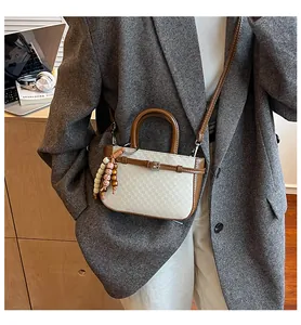Detail of a vintage mini beige crossbody bag with brown leather trim and retro bead charm