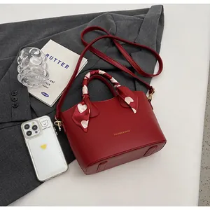 Détail du sac seau en cuir PU rouge avec poignée en foulard et lettrage doré chic