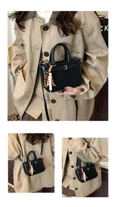 Detail of black woven texture handbag with stylish wooden bead pendant and buckle decor