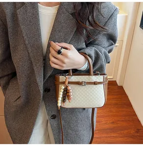 Close-up of vintage checkered crossbody bag with leather handles and beaded charm detail