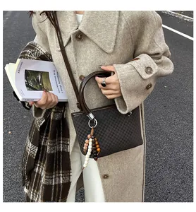 Close-up of a coffee checkered tote bag with brown handles and a beaded tassel detail