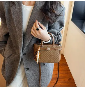 Close-up of brown crossbody bag with checkered texture and decorative beaded keychain