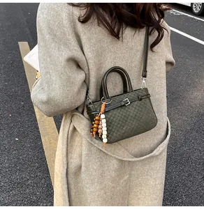 Detail of vintage green crossbody bag with leather strap and decorative beaded pendant