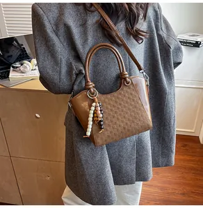 Détail d'un sac seau marron tissé avec pompon en perles de bois et cuir PU texturé