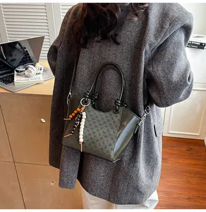 Détail du sac seau vert avec texture à carreaux et gland en perles dans un décor lifestyle