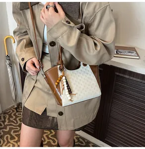 Détail d'un sac seau bicolore avec texture en cuir et breloque en perles colorées