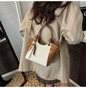 Détail du sac seau patchwork à damier avec breloque en perles colorées et anses en cuir brun