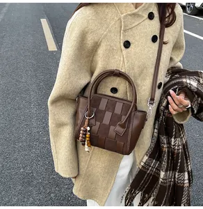Detail of woven patchwork crossbody bag with decorative wooden beads on winter coat
