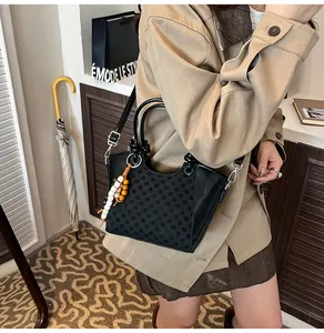 Vue détaillée du sac seau à damier avec finitions en cuir et breloque pompon perlé