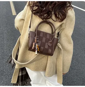 Detail of woven checkerboard leather handbag with vintage beads on autumn coat