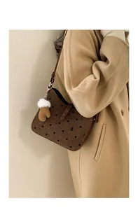 Close-up of a brown polka dot canvas bag with leather strap and plush glove charm decoration