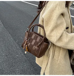 Close-up of woven texture and colorful bead charm on retro brown crossbody handbag