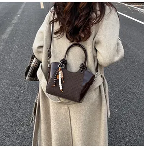 Détail du sac seau marron foncé avec motif à carreaux et pendentif à glands ethnique
