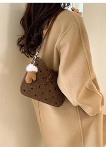Detailed shot of brown polka dot shoulder bag with cute glove pendant on winter coat
