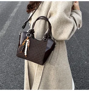 Détail d'un sac seau marron foncé avec empiècements texturés et pampille à perles