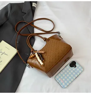 Détail d'un sac seau marron vintage avec texture en cuir tressé et perles en bois colorées