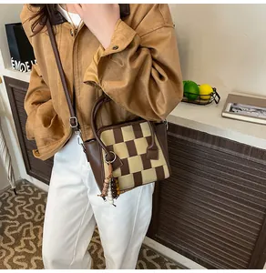 Detailed close-up of woven checkerboard handbag with wooden beads and tassel accent