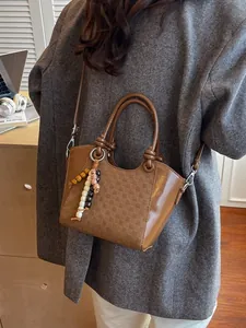Sac seau marron à damier avec perles en bois porté par un mannequin dans un bureau chic