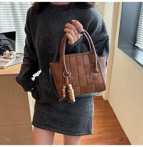 Close-up of woven leather texture and beaded charm on brown vintage shoulder bag
