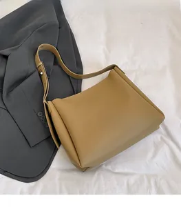 Close-up of khaki tote bag showing matte leather texture and wide shoulder strap
