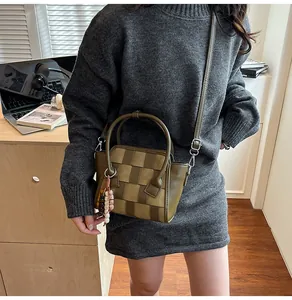 Detailed texture of olive green woven crossbody bag with beaded charm and slim strap