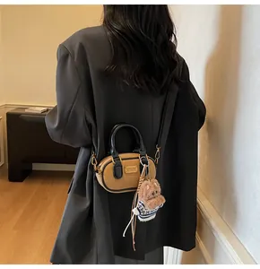 Close-up of brown baguette bag with black trim and a cute plush bear charm
