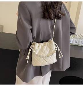 Close-up of quilted bucket bag featuring a pearl handle and drawstring chain strap